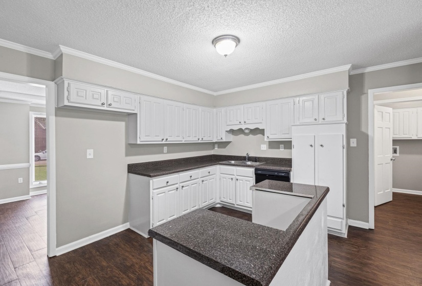 Kitchen featuring white cabinetry, dark stone-finish countertops, and dark wood-finish flooring