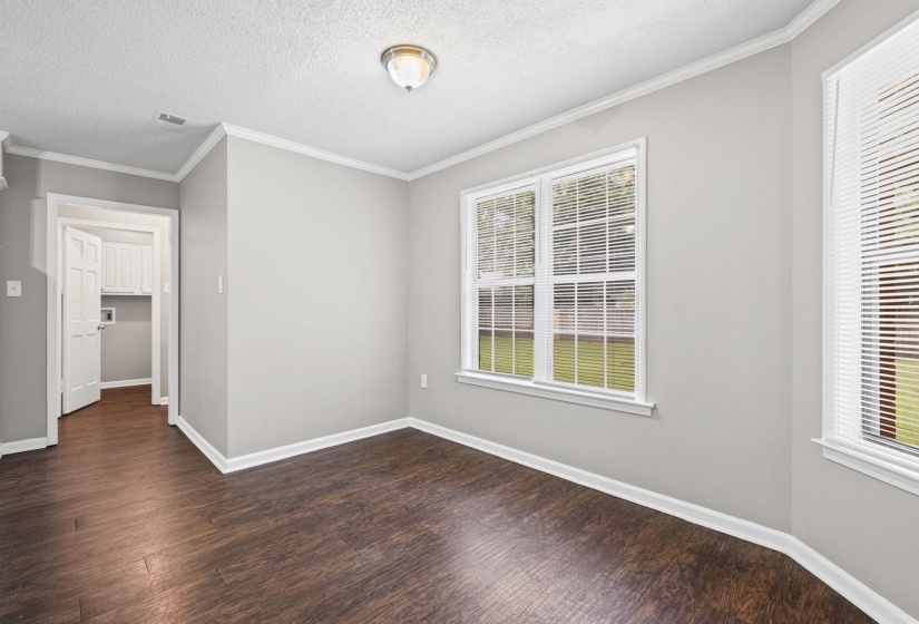 Room featuring two windows with white blinds, dark wood-finish flooring, and light gray walls
