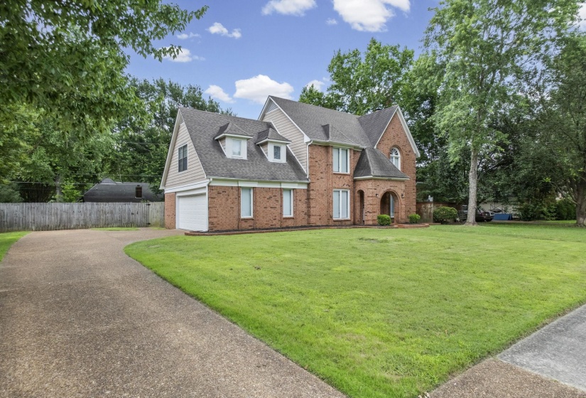 Traditional brick home featuring a pitched roof, dormer windows, and an arched entry