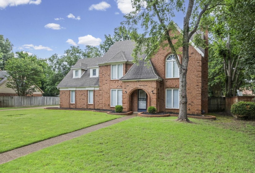 Brick two-story residence featuring a gabled roofline and multiple dormer windows