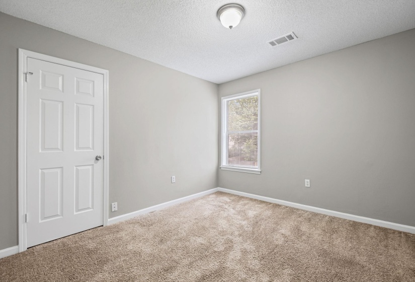 Carpeted room featuring a single window, a six-panel interior door, baseboard molding, and a ceiling-mounted light fixture