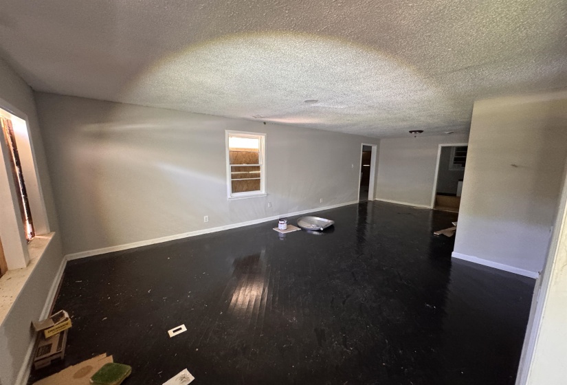 Spacious room featuring dark wood-finish flooring, light gray wall paint, and white trim