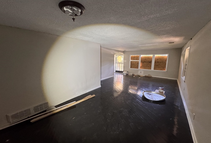 Spacious interior with dark wood-finish flooring, light-toned wall paint, and a textured ceiling