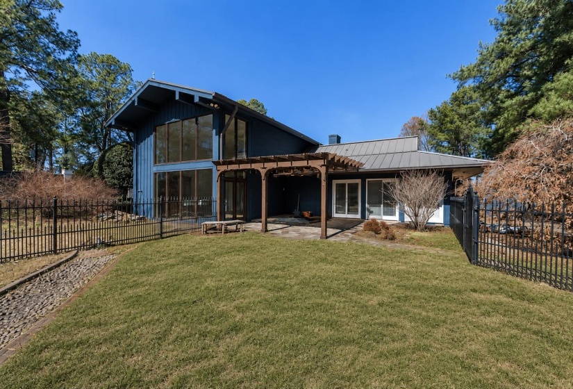 Rear exterior featuring a large lawn, a dark blue facade, and a metal roof