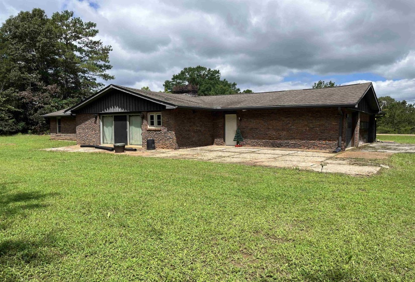 Brick exterior with a dark shingle roof and a concrete patio