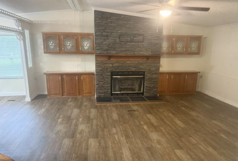 Stone fireplace with a wood-finish mantel and hearth, flanked by built-in wood cabinetry with decorative glass inserts