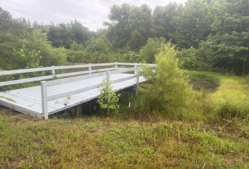 Painted wooden bridge with white railings spanning a natural water feature