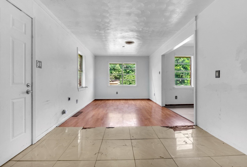 Room featuring a white paneled door, multiple windows, wood-finish flooring, and white walls