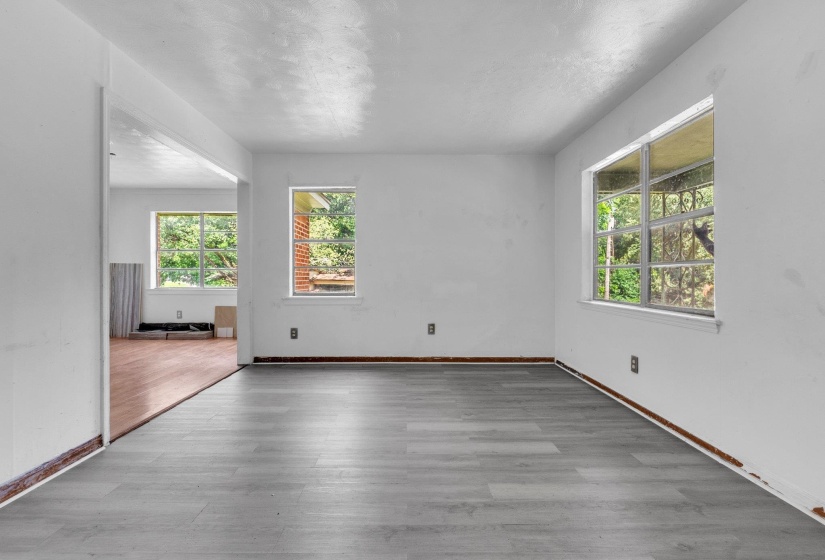 Spacious room featuring gray wood-finish flooring, white walls, and multiple windows