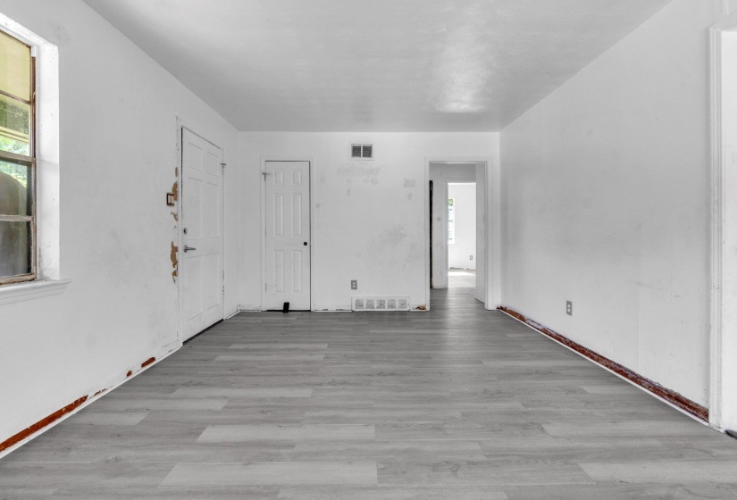 Spacious interior with light wood-finish flooring, white walls, and multiple doorways