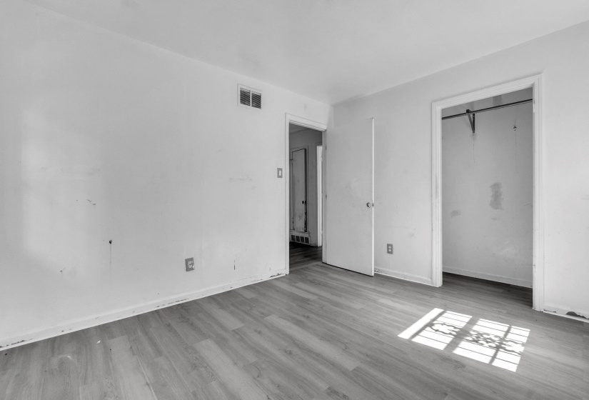 Wood-finish flooring throughout the room with white baseboards and walls