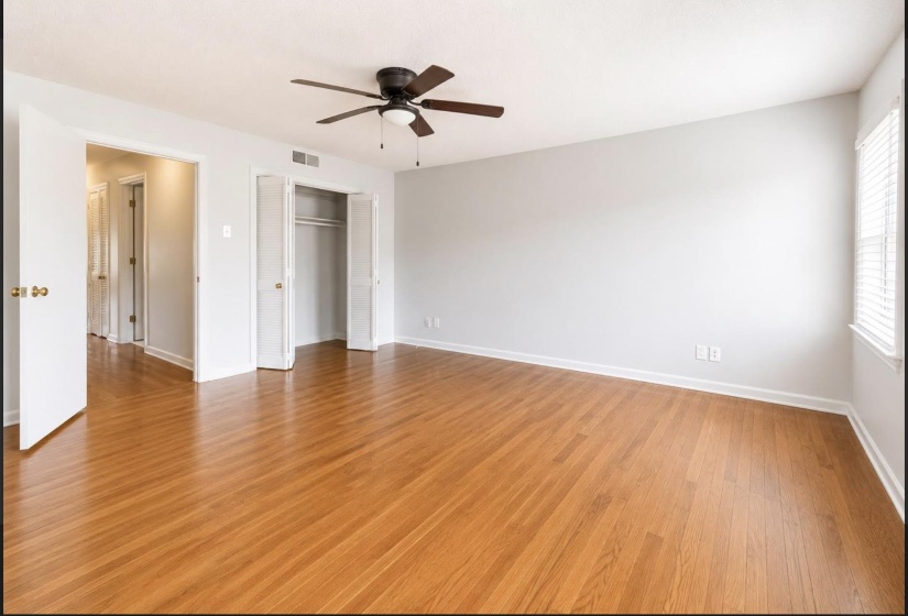 Bright room featuring wood-finish flooring, a ceiling fan with light fixture, and a window with horizontal blinds
