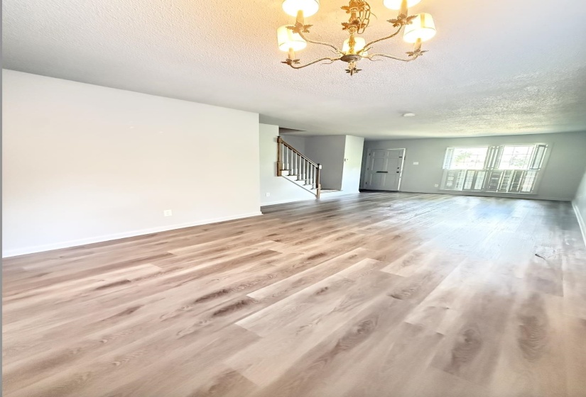 Spacious interior featuring light wood-finish flooring, a classic chandelier, and white wall finishes