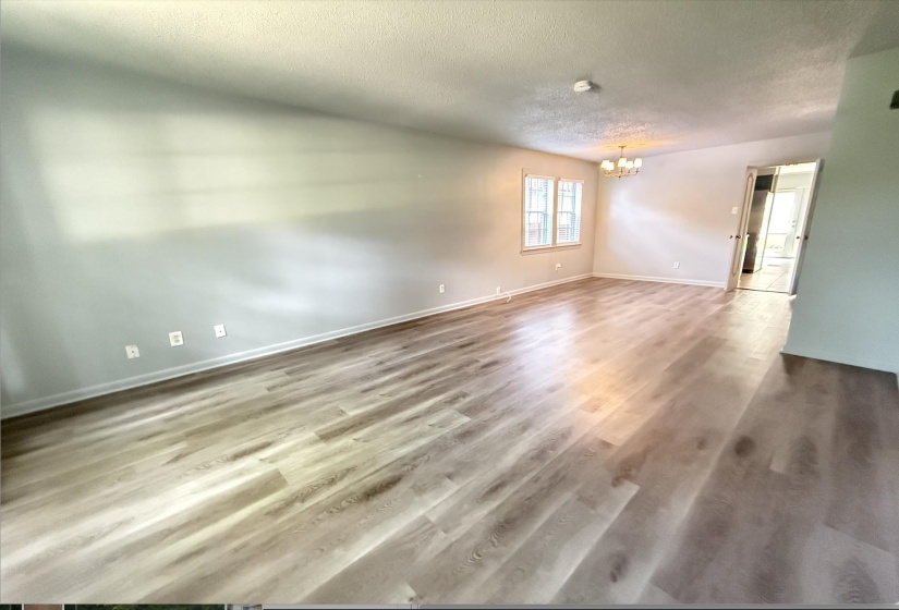 Spacious interior featuring light wood-finish flooring throughout, smooth light gray walls, and white baseboards