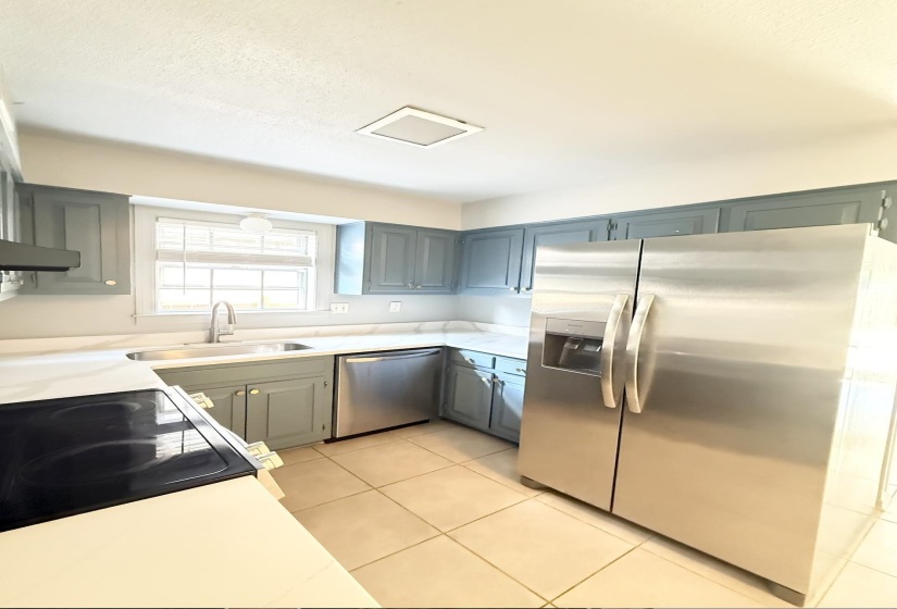 Kitchen featuring pale blue cabinetry, stainless steel appliances, white countertops, and tile flooring