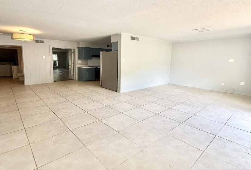 Open-concept living area with light-toned square tile flooring extending throughout
