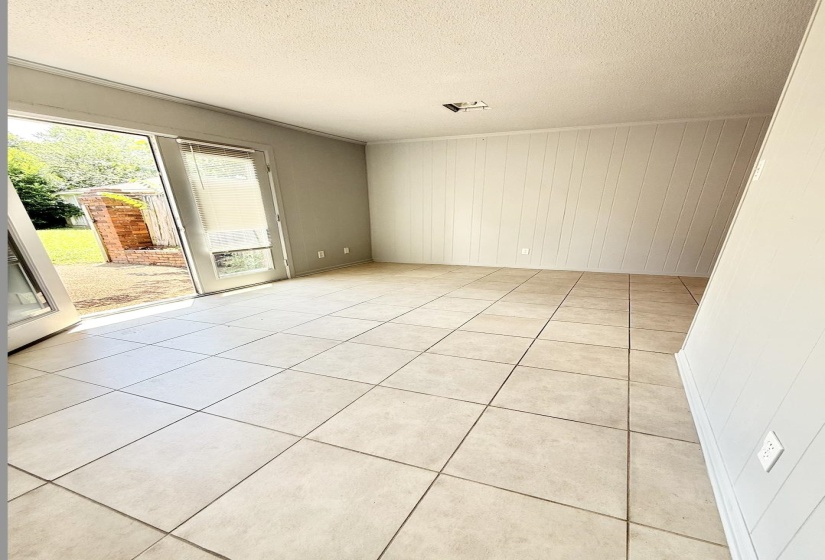 Ceramic tile flooring spans this room, featuring light gray paneled walls and a white textured ceiling