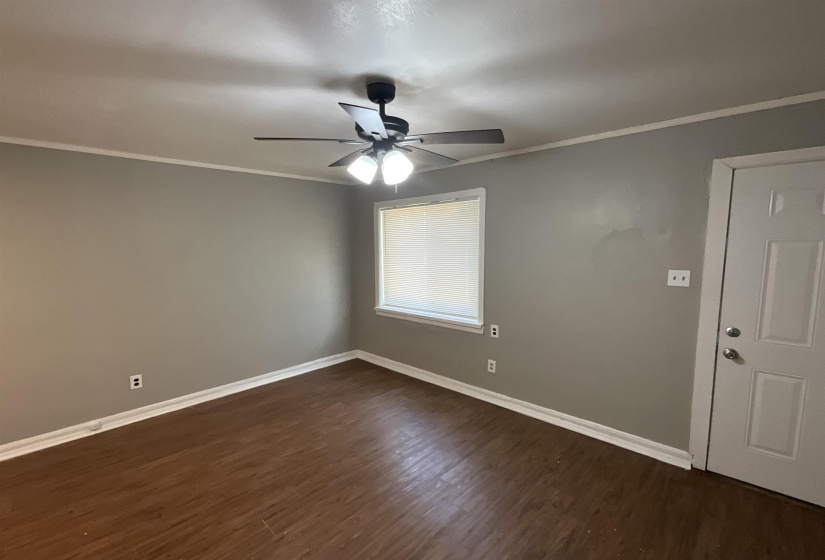 Unfurnished room with dark wood-style floors, crown molding, baseboards, and ceiling fan