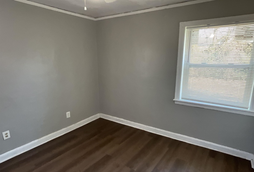 Unfurnished room featuring crown molding, ceiling fan, dark wood-style flooring, and baseboards