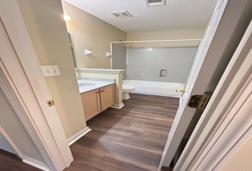 Full bath featuring vanity, a textured ceiling, dark wood-style floors, and bathing tub / shower combination