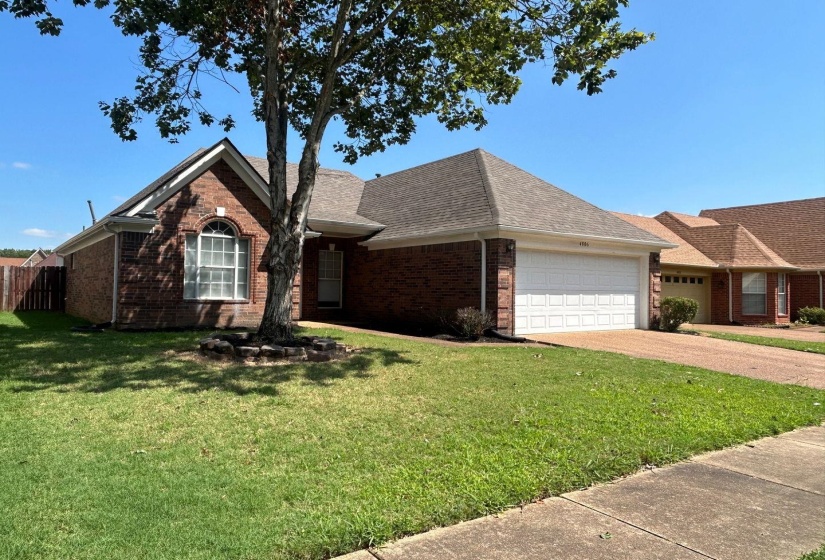View of front facade with brick siding, driveway, roof with shingles, and a garage