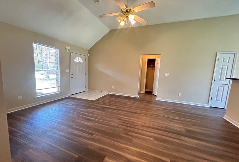 Unfurnished living room featuring dark wood-style flooring, a ceiling fan, and high vaulted ceiling