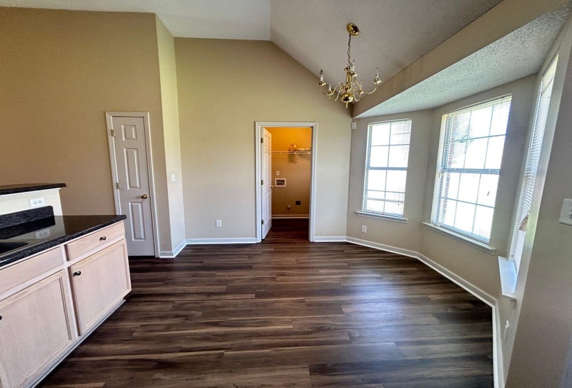 Unfurnished dining area with a chandelier, dark wood-style flooring, and high vaulted ceiling