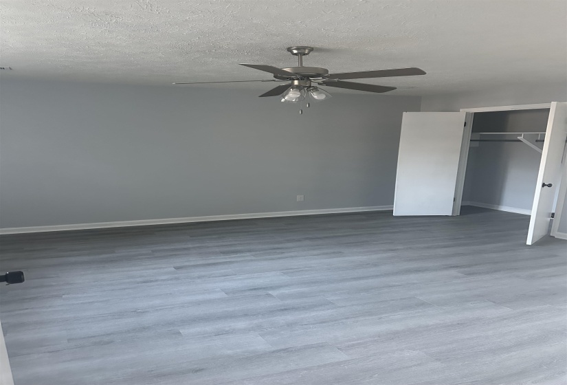 Unfurnished bedroom featuring ceiling fan, light wood finished floors, a closet, and a textured ceiling
