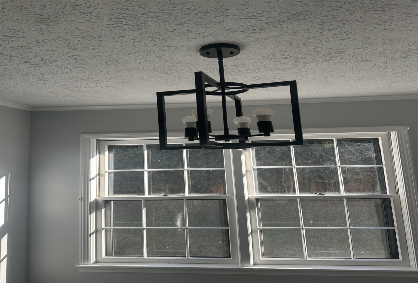 Detailed view of crown molding, a textured ceiling, and a chandelier