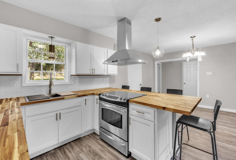Kitchen with wood counters, a peninsula, a kitchen breakfast bar, electric range, and a textured ceiling