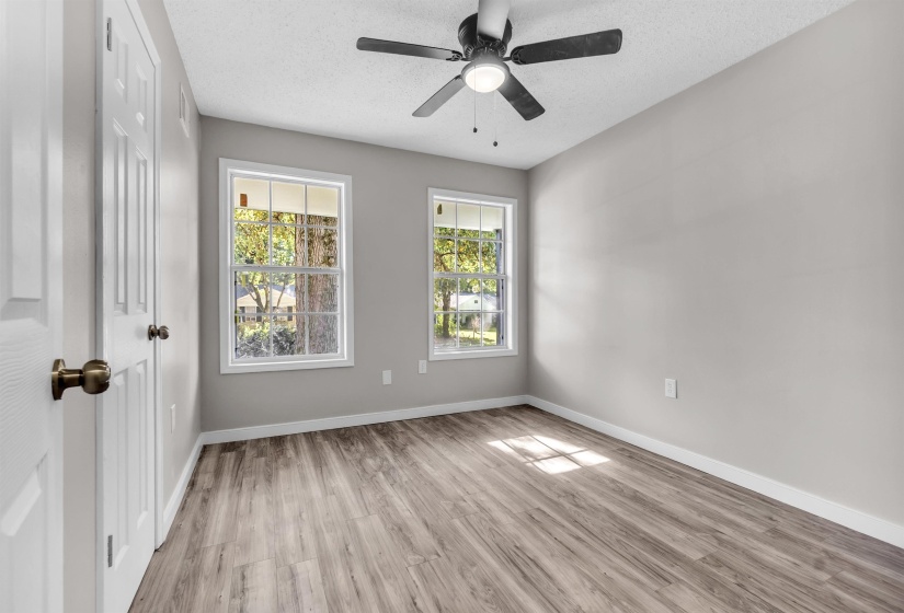 Empty room featuring light wood finished floors, a textured ceiling, and a ceiling fan