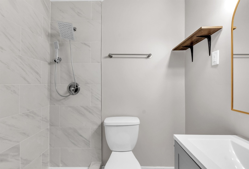 Bathroom featuring tiled shower and vanity