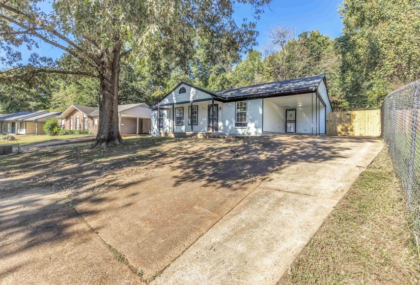 Single story home with driveway, a carport, and covered porch
