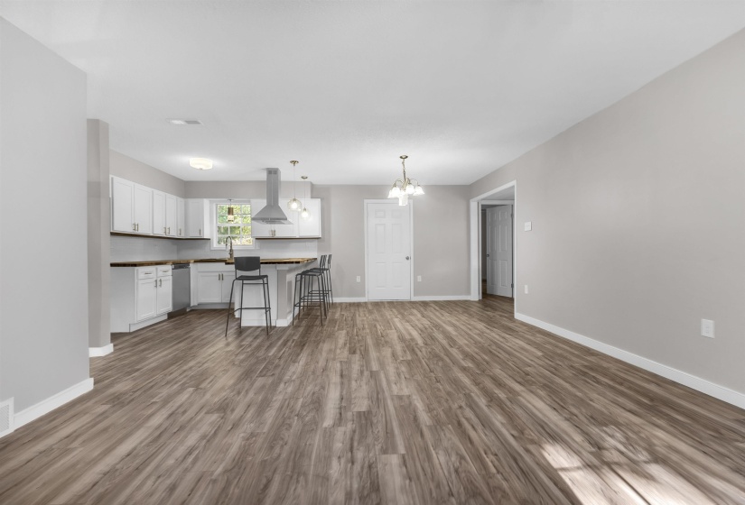 Kitchen featuring dark countertops, white cabinetry, a breakfast bar, ventilation hood, and dark wood finished floors