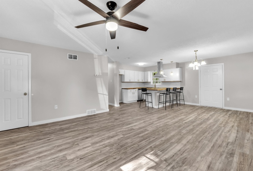 Living room with a ceiling fan, hanging lights, and light wood-type flooring