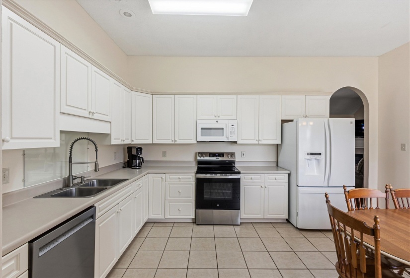 Spacious kitchen featuring extensive white cabinetry, light-toned countertops, and tile flooring