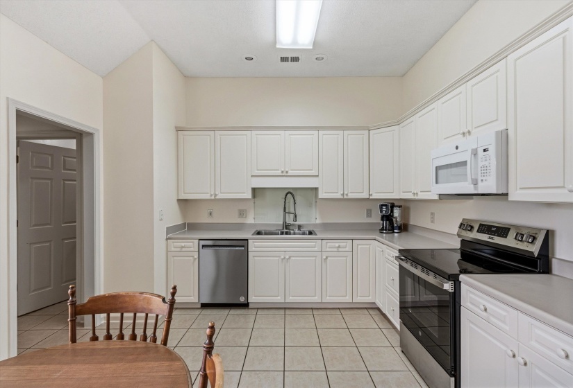 Kitchen featuring white cabinetry with brushed nickel hardware, laminate countertops, and tile flooring