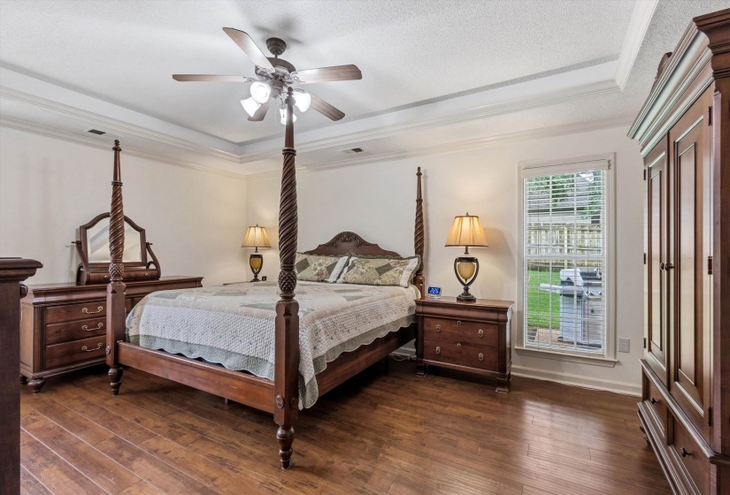 Spacious room with wood-finish flooring, white walls, and a tray ceiling