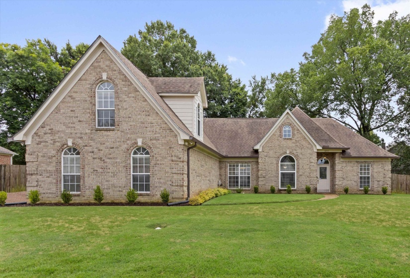 Brick facade residence with a pitched roofline, arched windows, gabled dormer, and a covered front entry