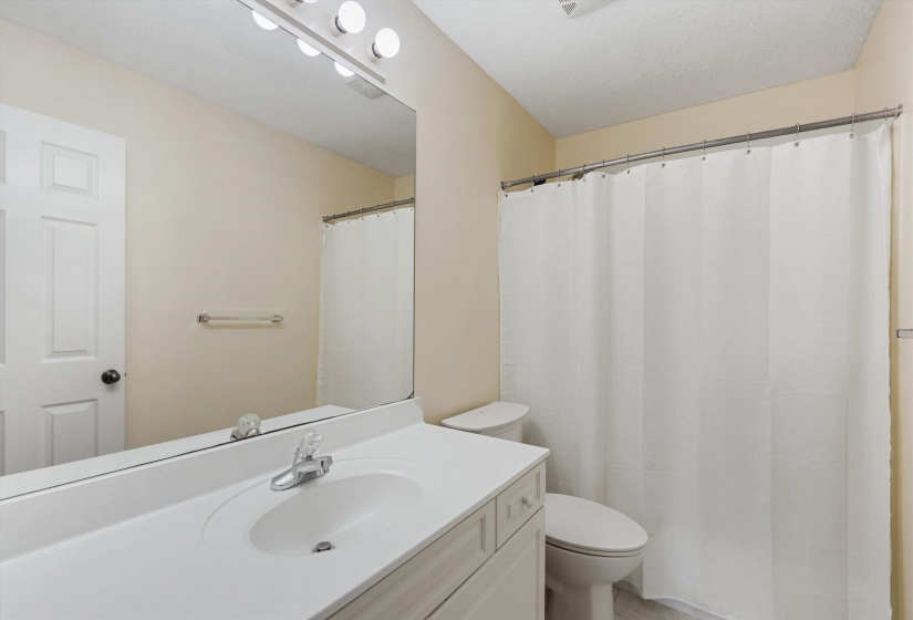 Bathroom featuring a white vanity with an integrated sink, chrome faucet, and a large wall-mounted mirror