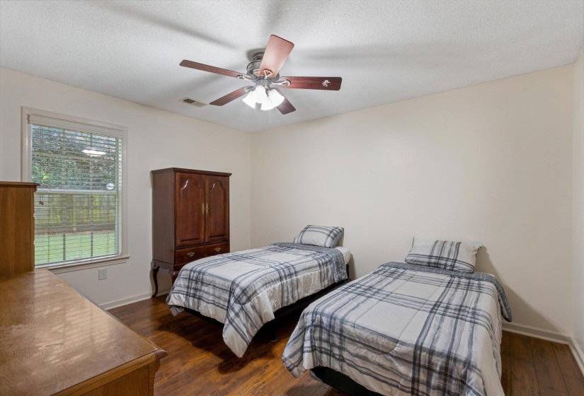 Bedroom featuring wood-finish flooring, a ceiling fan, and a window with blinds