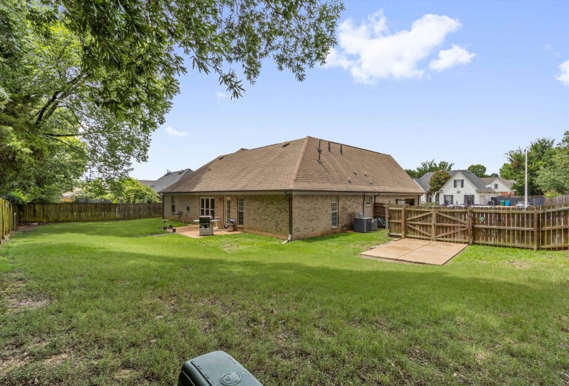Spacious backyard featuring a manicured lawn, full privacy fencing, and mature trees