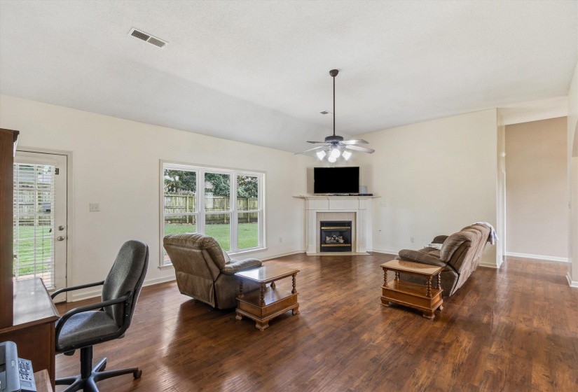Spacious interior featuring wood-finish flooring, a corner fireplace with a mantel, vaulted ceilings, and a ceiling fan