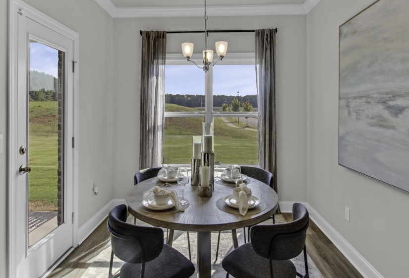 Dining space featuring wood finished floors, healthy amount of natural light, hanging lights, and ornamental molding