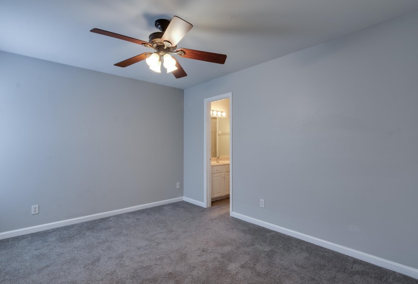 Carpeted room featuring a ceiling fan with integrated lighting, light gray wall paint, and white baseboards