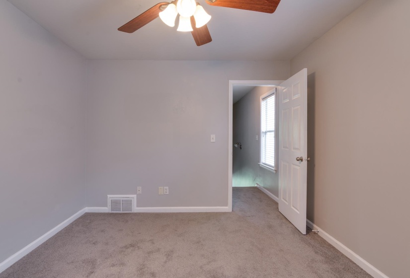 Carpeted interior room featuring light gray wall paint, white baseboards, and a ceiling fan with integrated lighting