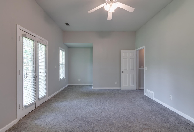 Carpeted room with vaulted ceilings and a ceiling fan