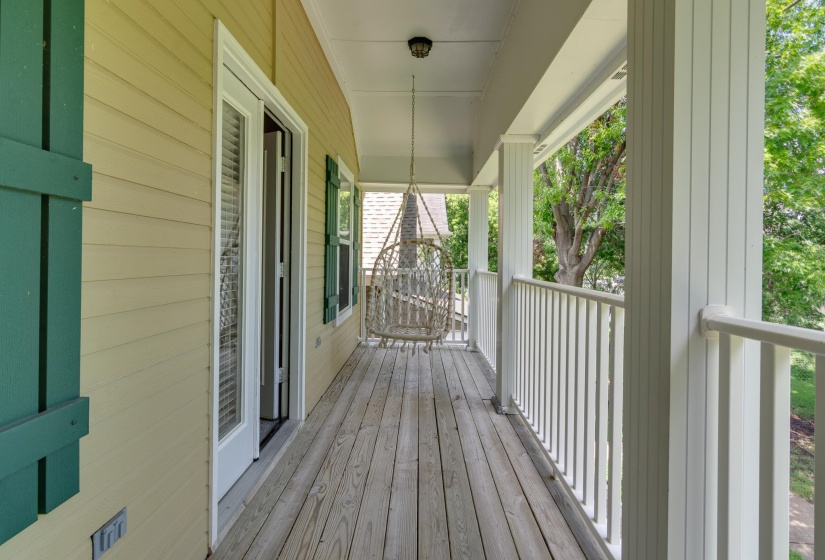 Expansive covered porch featuring wood-finish flooring, white baluster railings, and cream-colored siding