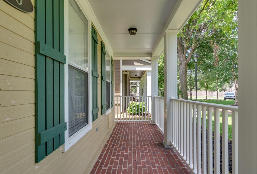 Inviting front porch featuring a brick-patterned walkway, white columns, and a white railing