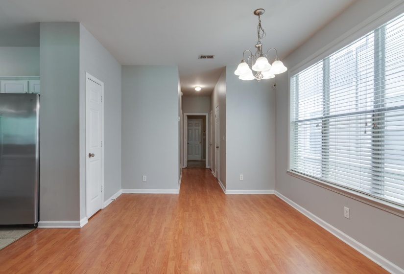 Spacious area featuring wood-finish flooring, light gray walls, and a large window with horizontal blinds
